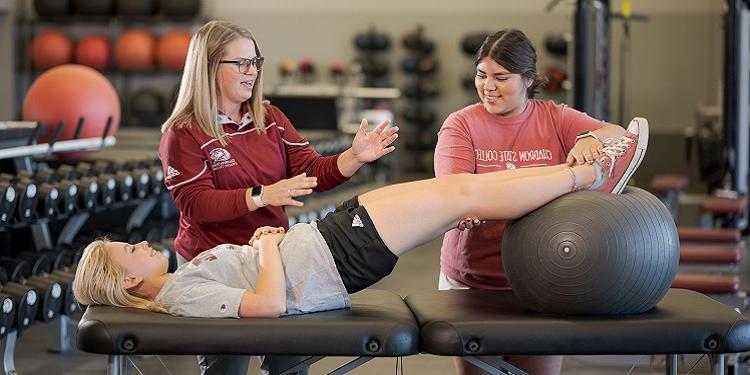 A woman showing teaching a student about athletic training with someone being examined
